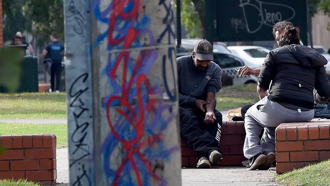 Drug users shoot up in the area while police speak to others in the background. Picture: Nicole Garmston