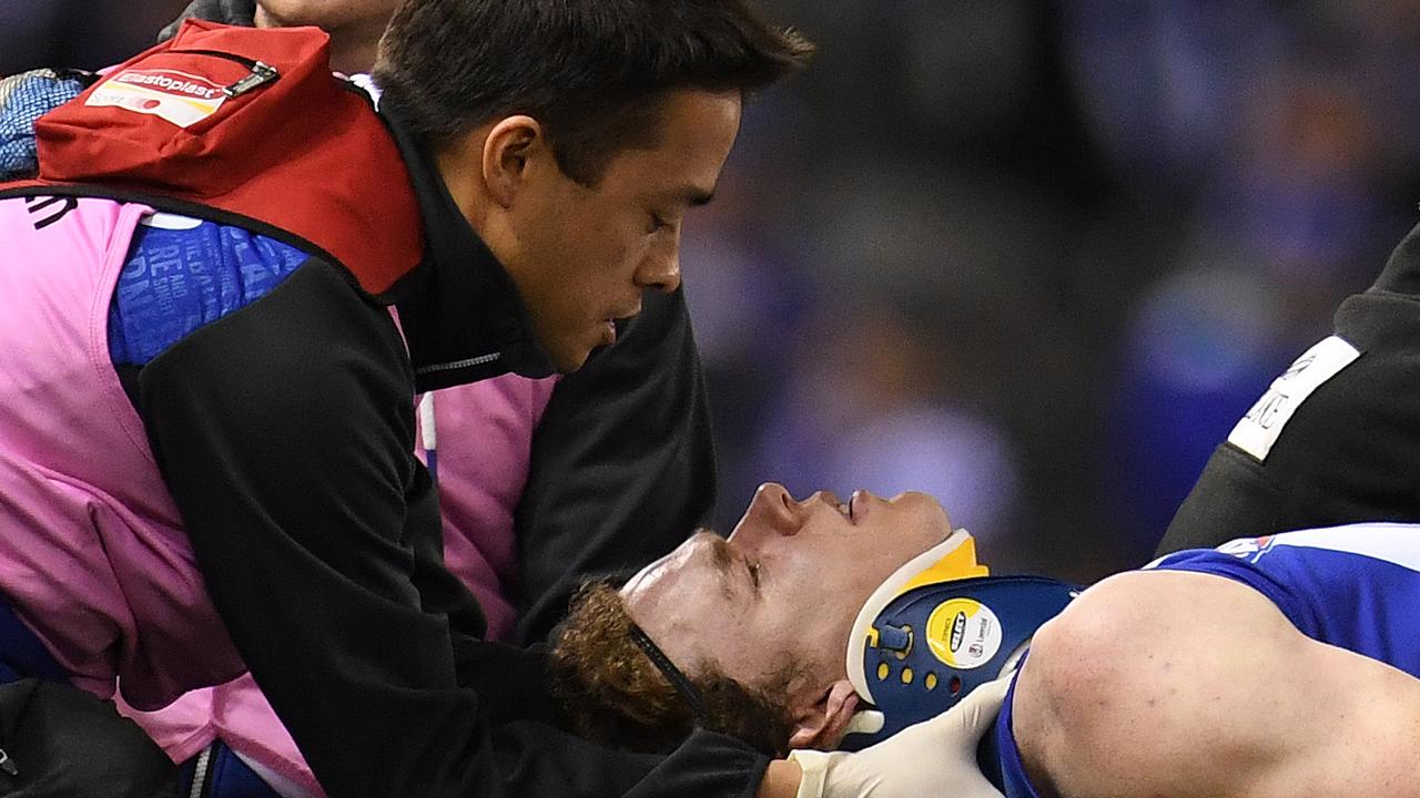 Ben Brown of the Kangaroos (right) is treated for concussion during round 20 in 2022.