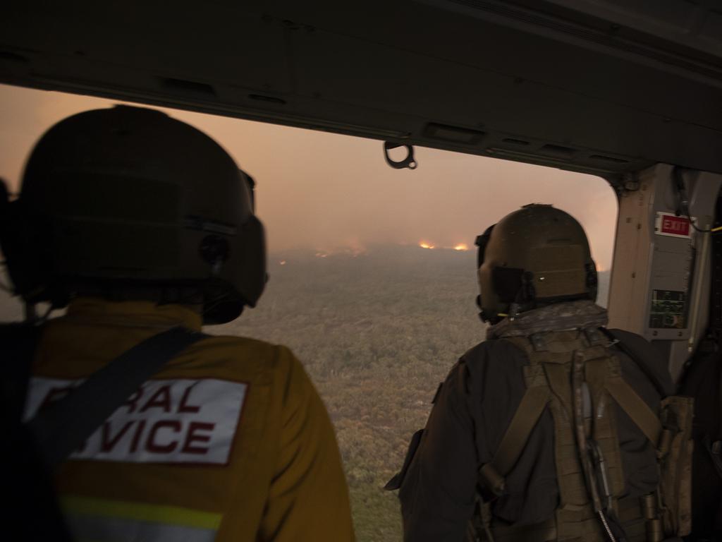 (l-r) Rural Fire Service employee Dwyane Graham and Royal Australian Navy Aircrewman Leading Seaman Brendan Menz view the Tianjara bushfire to the west of HMAS Albatross on an 808 Squadron MRH90 Taipan Military Support Helicopter. Picture: ADF