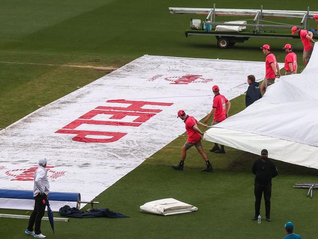 Groundsmen remove covers from over the pitch during a rain delay at the third cricket Test match between Australia and South Africa at the Sydney Cricket Ground (SCG) in Sydney on January 7, 2023. (Photo by DAVID GRAY / AFP) / -- IMAGE RESTRICTED TO EDITORIAL USE - STRICTLY NO COMMERCIAL USE --