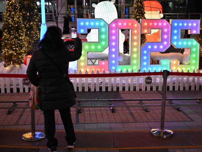 A woman takes a photo in front of a 2025 luminous sign before a countdown event to celebrate the New Year in Seoul on December 31, 2024. Picture: Jung Yeon-je / AFP