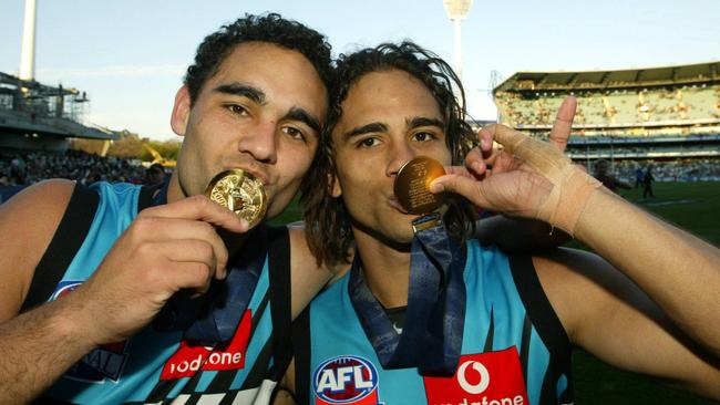 Brothers Shaun (L) and Peter Burgoyne (R) kiss their premiership medals at the MCG after winning the 2004 AFL grand final with Port Adelaide against Brisbane. Picture: News Corp.