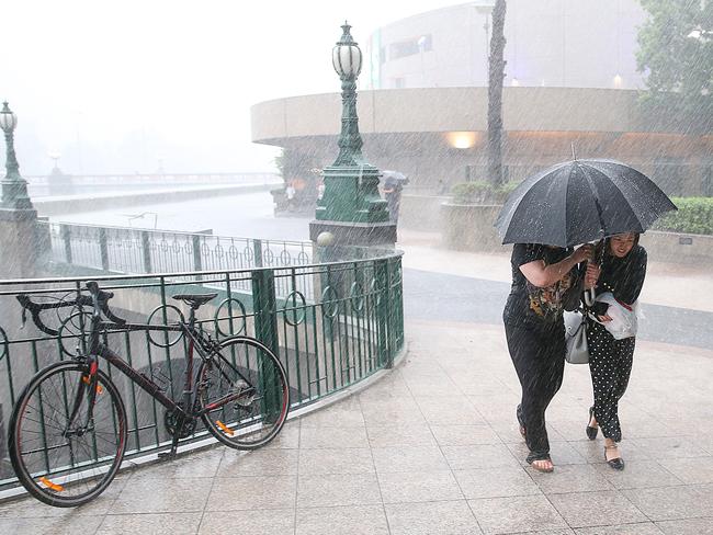 Two women rush for shelter as the storm hits Southbank. Picture: Ian Currie