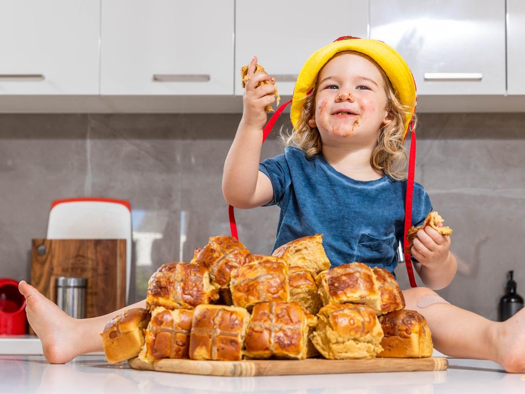 Vegemite hot cross buns will be in in Coles for the first time. Micah Pamio eats the new buns. Picture: Jake Nowakowski