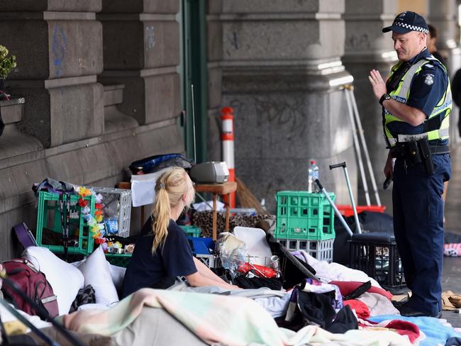 Police speak to a woman who lashed out at reporters outside Flinders St station. Picture: Nicole Garmston