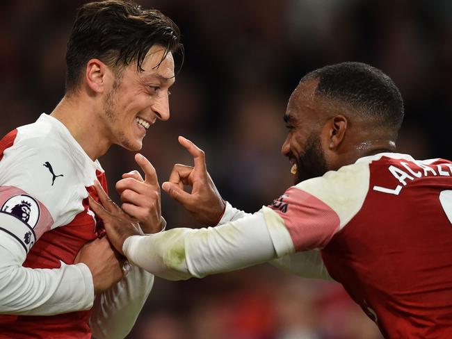 Arsenal's German midfielder Mesut Ozil (L) celebrates with Arsenal's French striker Alexandre Lacazette after scoring their first goal during the English Premier League football match between Arsenal and Leicester City at the Emirates Stadium in London on October 22, 2018. (Photo by Glyn KIRK / IKIMAGES / AFP) / RESTRICTED TO EDITORIAL USE. No use with unauthorized audio, video, data, fixture lists, club/league logos or 'live' services. Online in-match use limited to 45 images, no video emulation. No use in betting, games or single club/league/player publications.
