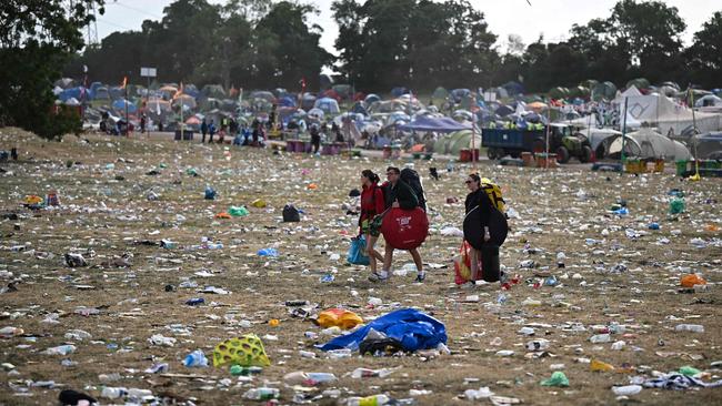 Festival-goers carry their belongings as they walk across a field covered in litter at the end of Glastonbury Festival. Picture: Oli Scarff / AFP