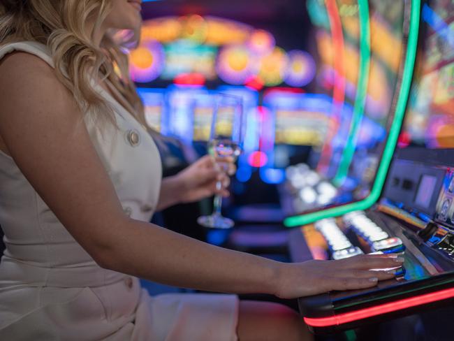 beautiful girl drinking wine alone at casino poker machine pokies istock generic