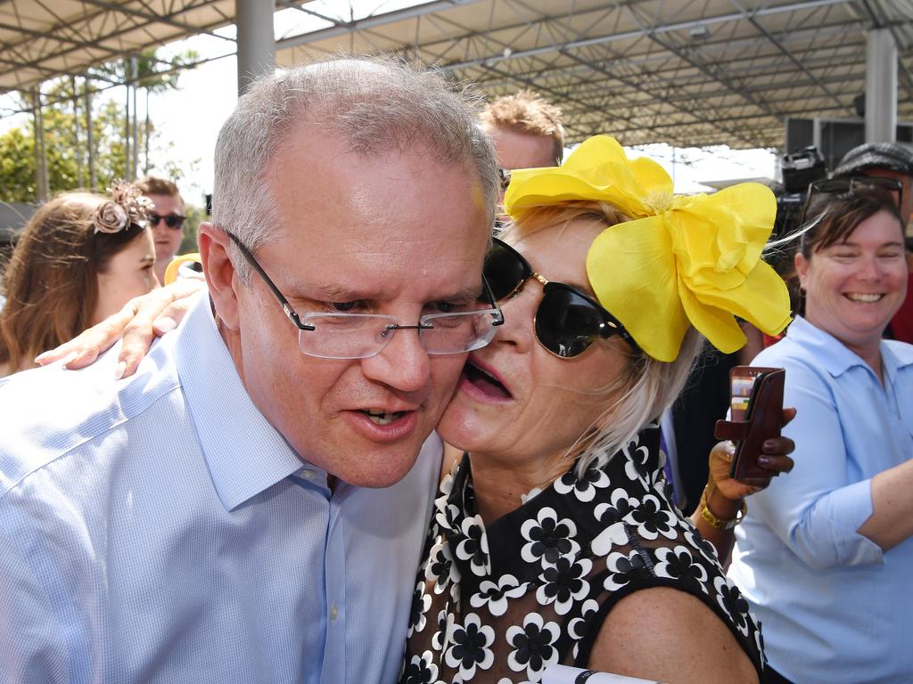 Australian Prime Minister Scott Morrison is kissed by a racegoer on Melbourne Cup day at the Corbould Park Racecourse on the Sunshine Coast, Tuesday, November 6, 2018. Mr Morrison is on a four-day bus tour of Queensland. (AAP Image/Dan Peled)