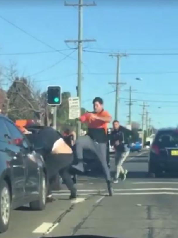 The footage shows four men fighting at the traffic lights in Merrylands