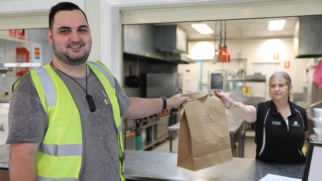 Peta Gerner handing over one of the Wynnum Golf Club’s meals to LocalYou’s Joshua Bentley.