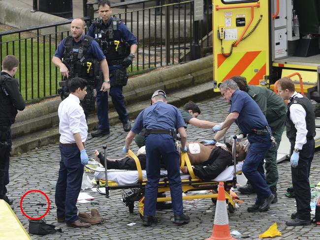 A man is treated by emergency services as police look on at the scene outside the Houses of Parliament. Picture: AP