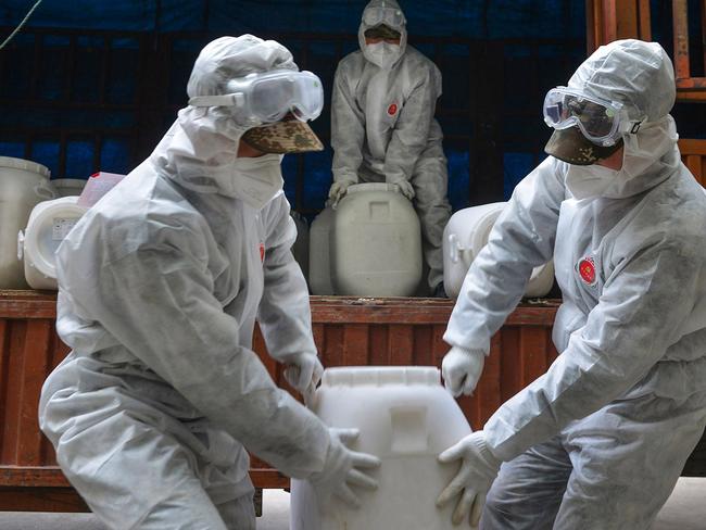 Chinese paramilitary police officers in protective gear transfer pails of disinfectant outside Xiaogan City where 5 million residents are under house arrest. Picture: AFP/China OUT