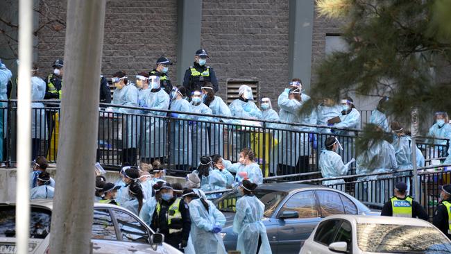 Police and healthcare workers prepare to enter one of the towers at the North Melbourne public housing estate. Picture: NCA NewsWire / Andrew Henshaw