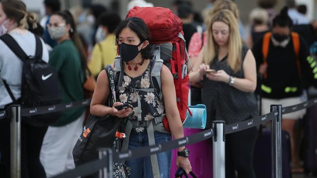 Passengers line up at Terminal 2 at Sydney Airport Departures this morning as travellers look to get out of Sydney. Picture: David Swift