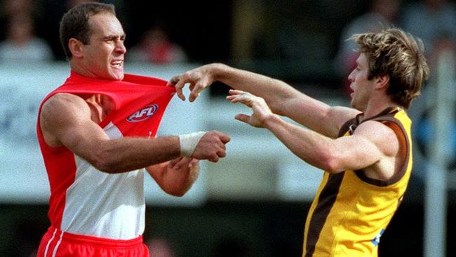 Wayne Schwass and Shane Crawford tangle during a footy match.