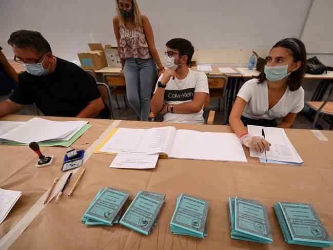 A view shows ballot papers for the constitutional referendum and voting officers wearing a face mask and one wearing gloves, at a polling station in downtown Rome. Italians head to the polls this weekend, for a referendum and Tuscan-led regional elections. Picture: AFP