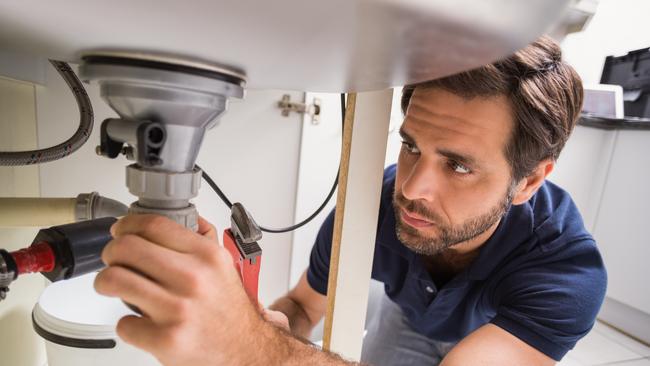 Plumber fixing under the sink in the kitchen. Photo: iStock