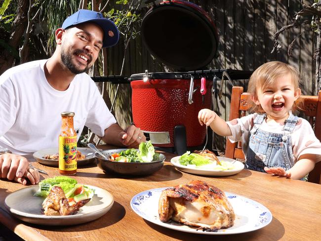 Chef Louis Tikaram enjoying BBQ peri peri chicken with his daughters Maelle, 4, and Colette, 2, in the back yard at home, Norman Park. Picture: Liam Kidston.