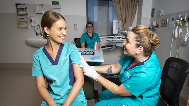 Registered Nurse Zoe Park receives Queensland’s first COVID-19 vaccine from clinical nurse consultant Kellie Kenway at Gold Coast University Hospital. Photo: Nigel Hallett.