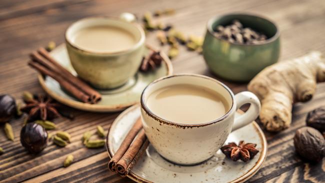 Traditional indian drink - masala chai tea (milk tea) with spices on wooden background