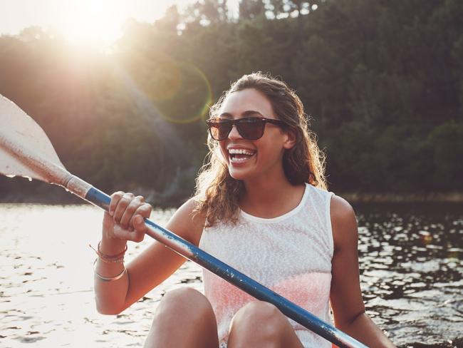 Wellbeing image for Gold Coast EyeSmiling young woman kayaking on a lake. Happy young woman canoeing in a lake on a summer day.