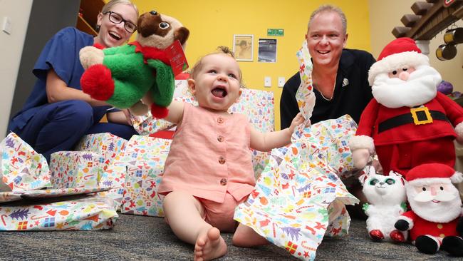 Nurse Emma McTaggart and Benowa Newsagency owner Andrew McTaggart watch little 10 month old Mia Elliott having fun at the hand over of gifts collected during their Christmas drive for sick kids at Pindara Private Hospital. Picture Glenn Hampson