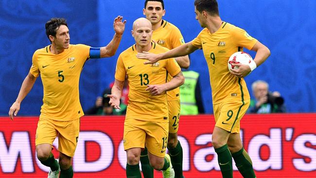 Australia's midfielder Mark Milligan (L) is congratulated teammates.