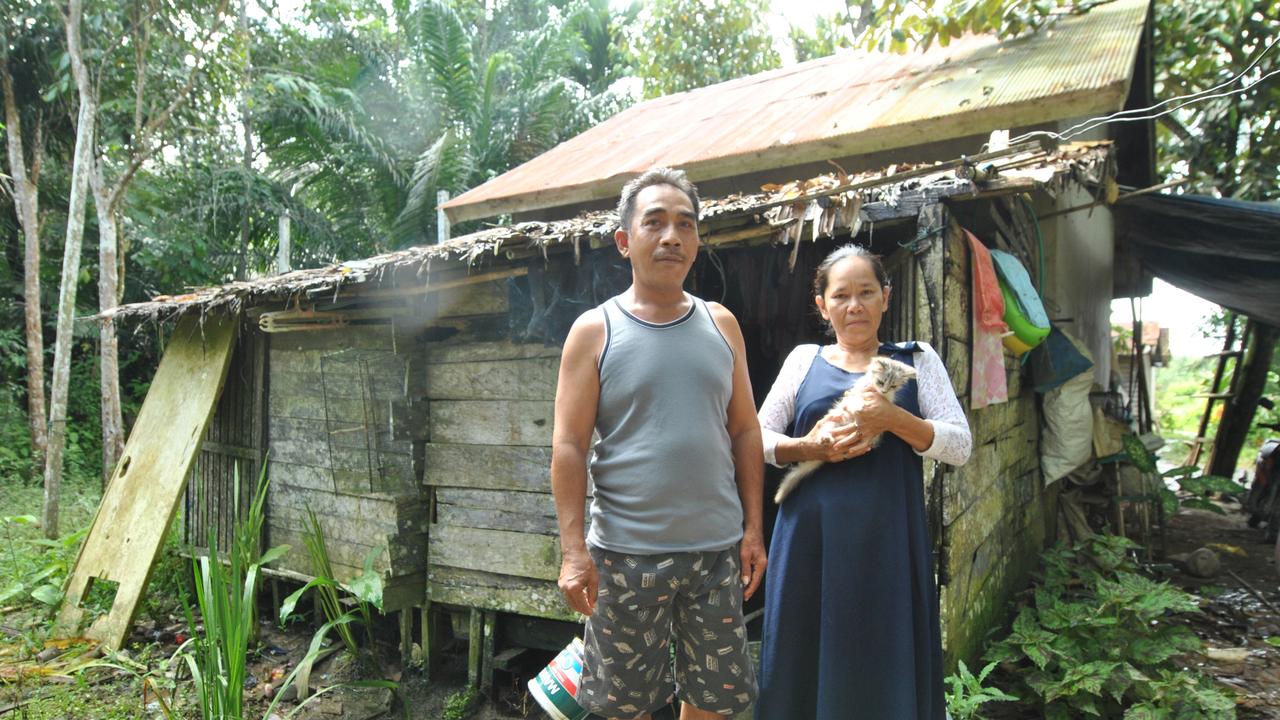 A couple in stand by their house affected by the construction of a dike in Sepaku, close to the core development region of Indonesia's new capital city in East Kalimantan.