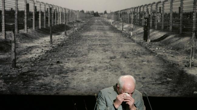 Holocaust survivor Kurt Julius Goldstein wipes away tears during his speech, in front of a photo of the Auschwitz concentration camp in Poland, during a commemoration marking an anniversary of the liberation of the camp. As a new wave of anti-Semitism sweeps the globe, it’s as if overnight, Auschwitz is forgotten. Picture: News Corp