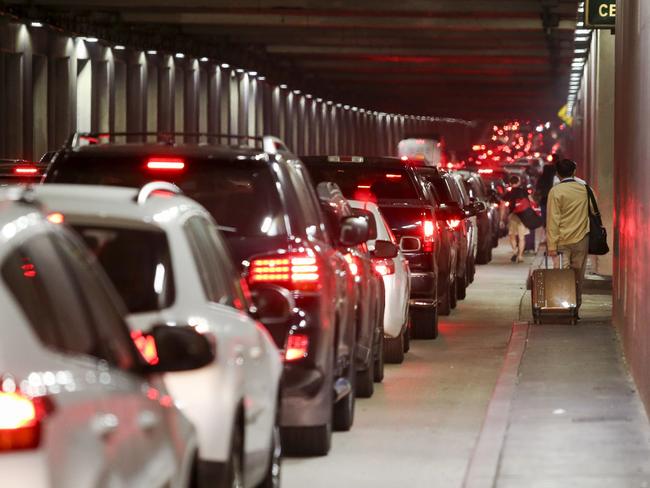 Passengers haul their luggage as they walk towards LAX after Sunday night’s shooting scare. Picture: Ringo H.W. Chiu