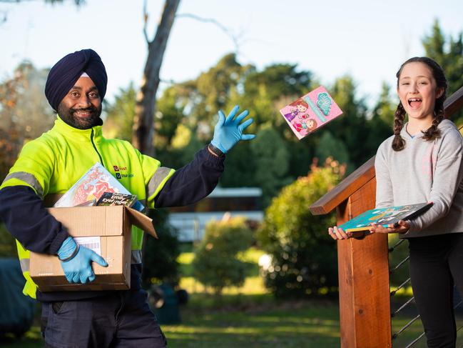 Tejinder Dhaliwal from Australia Post with Annnika, 8, getting her contactless book delivery. Picture: Jason Edwards