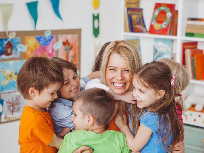 GCS - My Life - Day One Early Learning Centres.Kids in kindergarden playing with their teacher.They are hugging her to express their love.