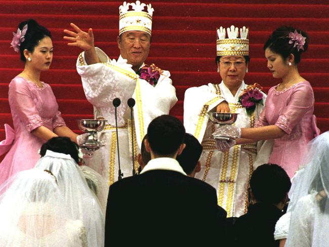 Sun Myung Moon and his wife Han Hak Ja sprinkle holy water onn young couples at a mass wedding in 2000.