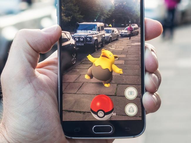 AUGMENTED REALITY Edinburgh, UK - July 18, 2016: Closeup of a man holding a Samsung S6 smartphone, playing Pokemon Go with the game's augmented reality superimposing a character onto the pavement surface, as a person approaches in the distance. Image: iStock For Study Options 2017 feature