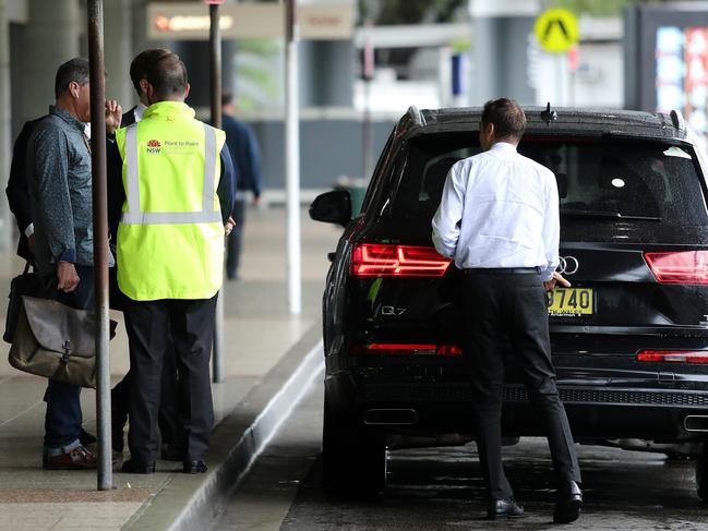 Point to Point Commission officers talk to passengers at the Sydney Airport domestic terminal Friday. Picture: Tim Hunter.