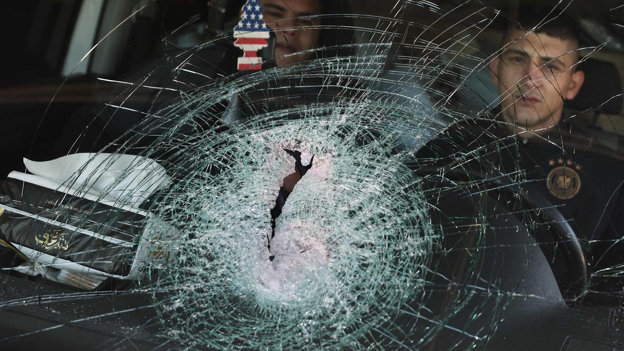 Men sit behind the shattered windshield of a vehicle following an attack by Israeli settlers in the Palestinian village of Jinsafut in the north of the occupied West Bank, on January 21, 2025. Picture: Jaafar Ashtiyeh / AFP