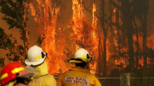 RFS crews battle an out-of-control fire near houses along Lemon Tree Passage Rd, in Salt Ash, on Friday morning. Picture: AAP