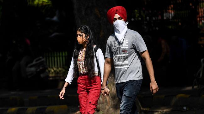 A woman wearing a face mask and a man wearing a protective scarf cross a street in the Indian capital New Delhi on Saturday. India is one of the three worst-hit countries in the pandemic based on official statistics. Picture: AFP