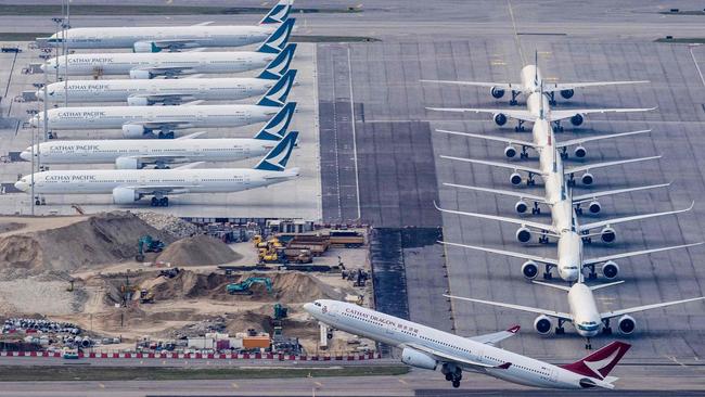 A Cathay Dragon passenger aeroplane takes off as Cathay Pacific aircraft are seen parked on the tarmac at Hong Kong's Chek Lap Kok International Airport. Picture: Anthony Wallace / AFP.