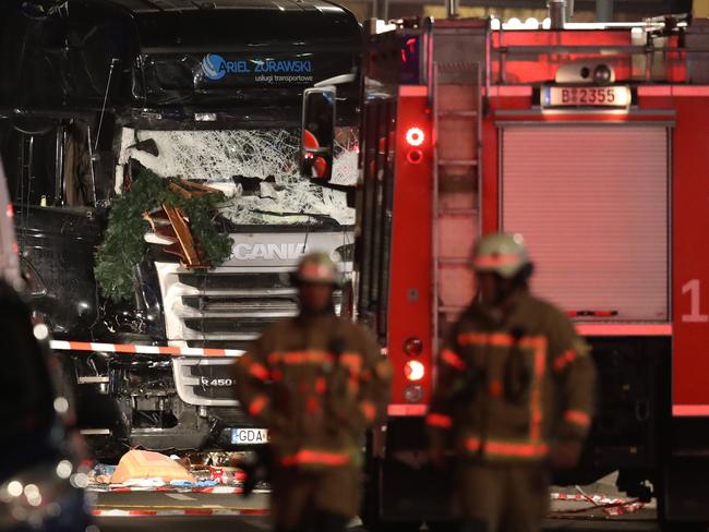 Glass is shattered on the windshield as rescue workers walk near the damaged lorry truck after it was ploughed through a Christmas market on December 19, 2016 in Berlin, Germany. Picture: Getty