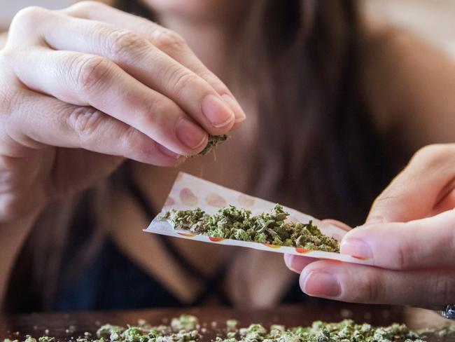 An anonymous woman placing marijuana flower into a joint paper to smoke.  Picture: istock