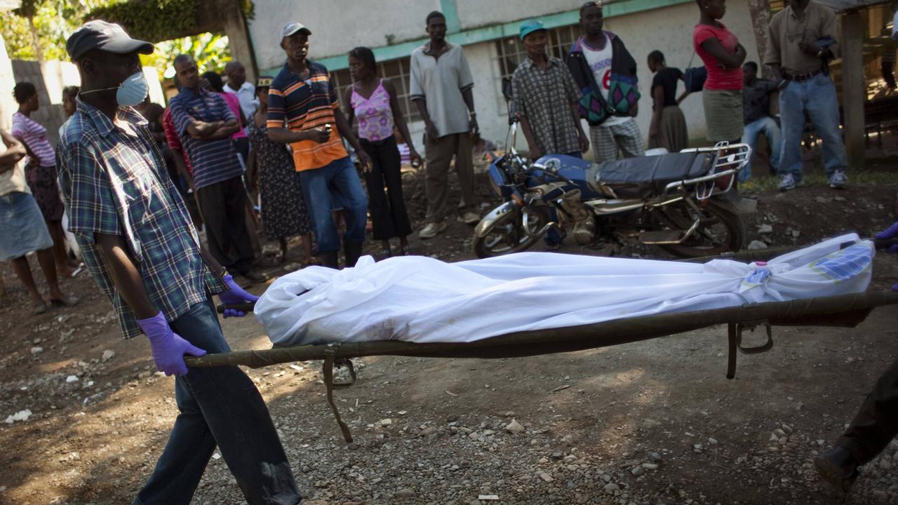 Workers carry the body of a Haitian woman who died from cholera.