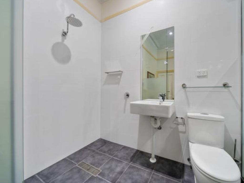 A boxy North Adelaide apartment featuring its own glass shower smack bang in the middle of the kitchen has listed for $400