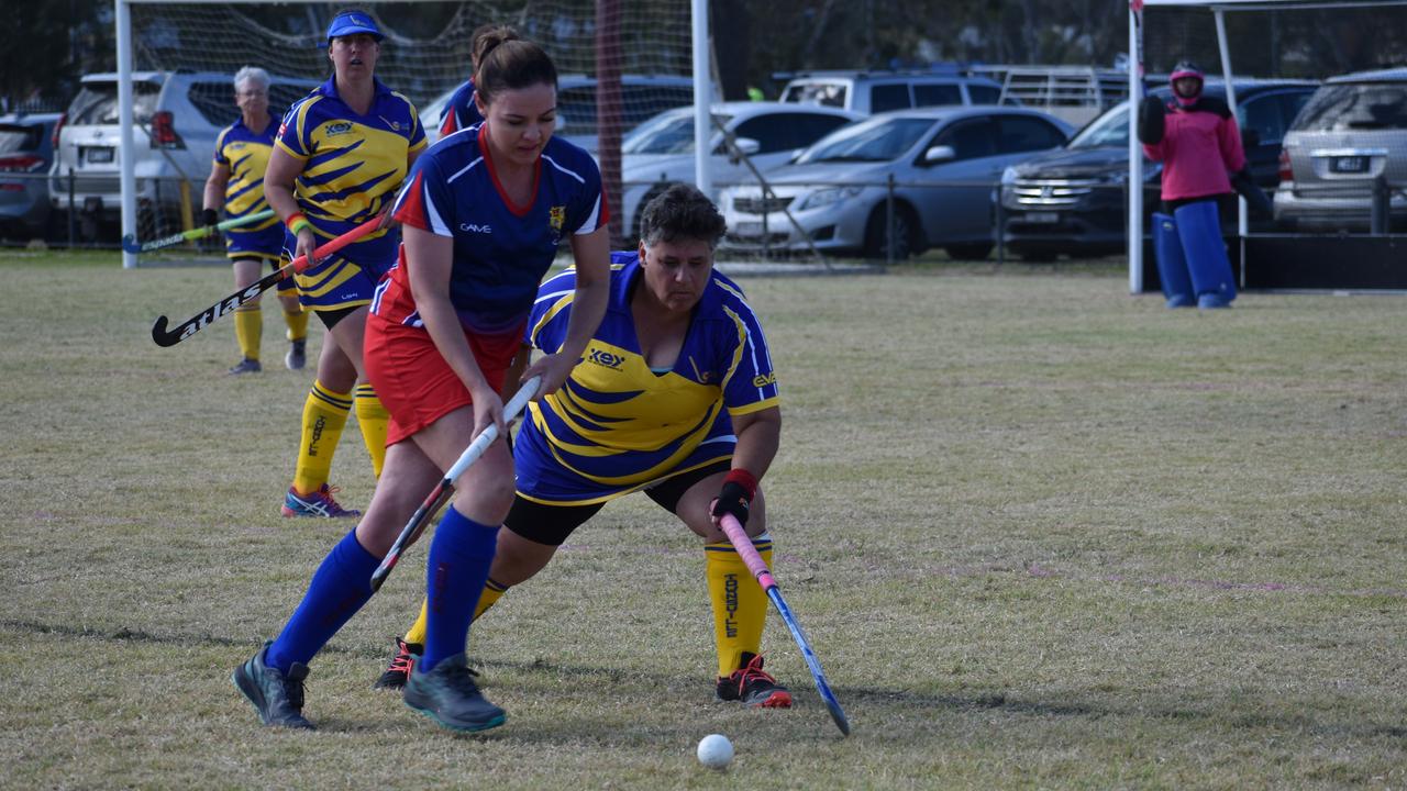 Warwick's Danielle Cook and Townsville's Lew Urquhart battle for possession in the clubs' match-up at the 2021 Queensland Hockey Women's Masters Championships.