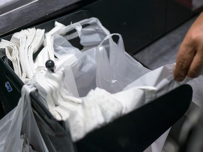 (FILES) In this file photo taken on June 30, 2014 a person picks up a plastic bag in a supermarket in Paris. - Two years after the ban on single-use plastic bags in France the result is disappointing. (Photo by Fred DUFOUR / AFP)