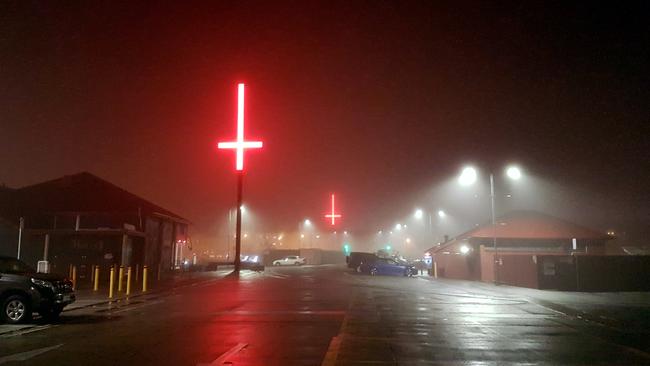 The Dark Mofo crosses light up a foggy night on the Hobart waterfront.