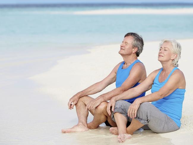 Senior Couple In Sports Clothing Relaxing On Beautiful Beach