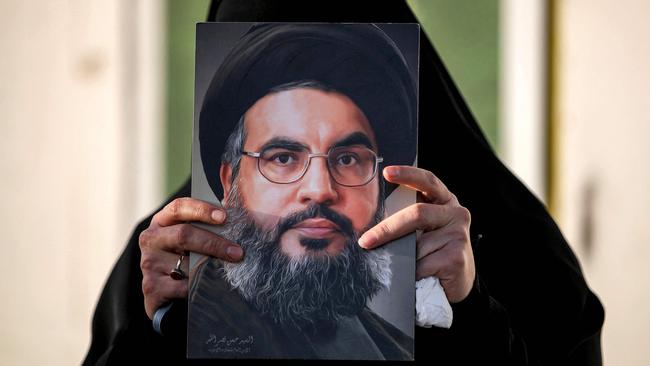 A woman holds up a painting of slain Hezbollah leader Hassan Nasrallah who was killed in an Israeli air strike in Beirut. Picture: Ahmad Al-Rubaye/AFP