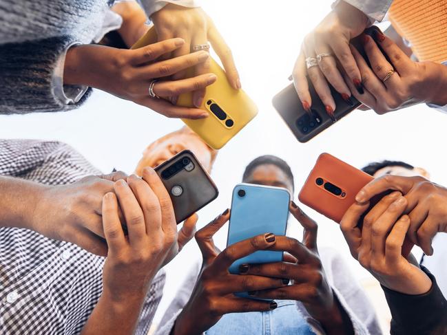 Teens in circle holding smart mobile phones - Multicultural young people using cellphones outside - Teenagers addicted to new technology concept